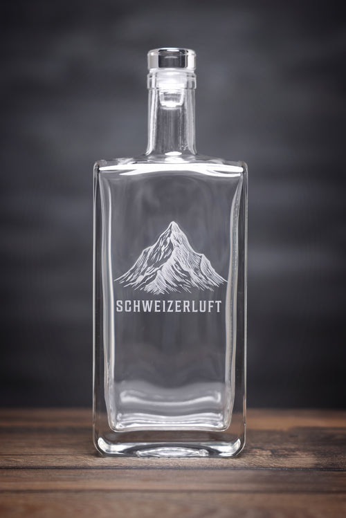 SchweizerLuft® Summit Edition 500 ml glass bottle with engraved Swiss mountain design on dark background