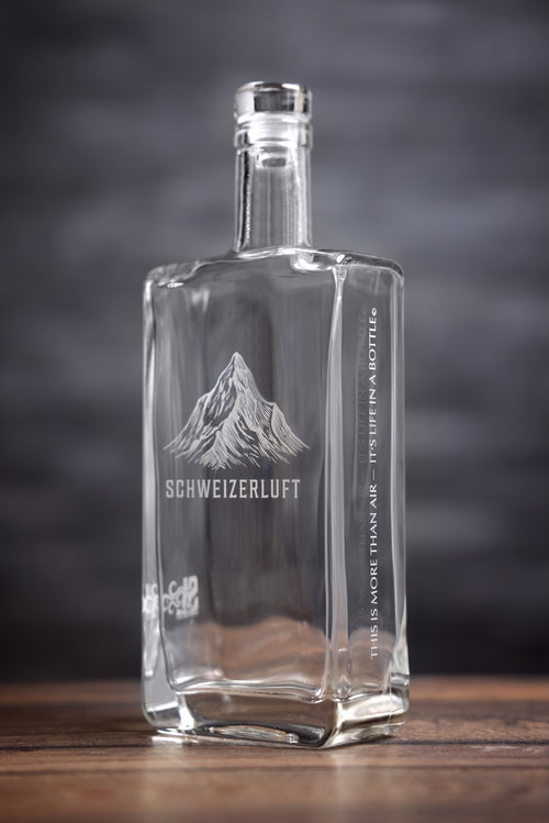 SchweizerLuft® Summit Edition 500 ml glass bottle, angled view with engraved Swiss mountain design.