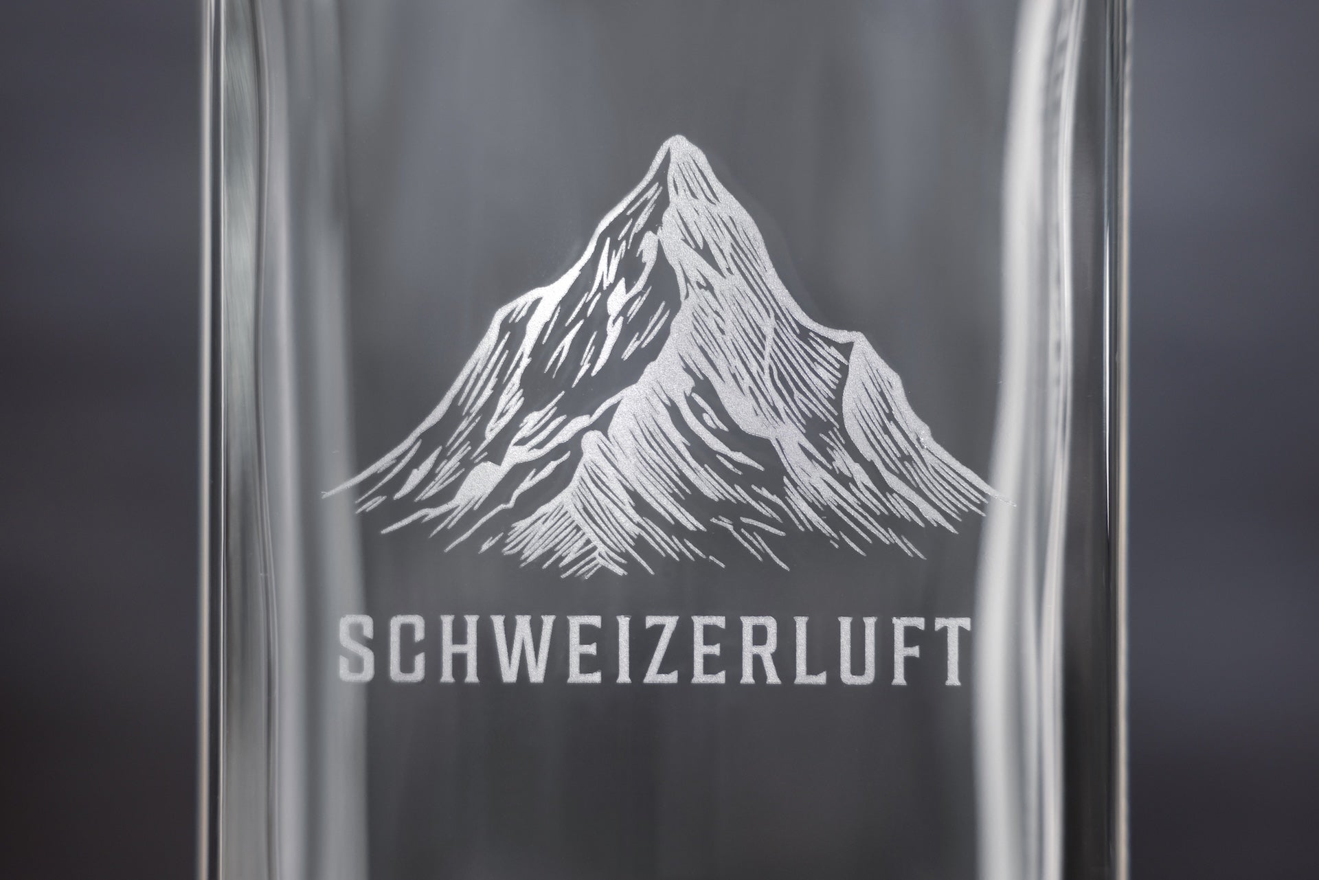 Close-up of engraved Swiss mountain and SchweizerLuft® logo on glass bottle.